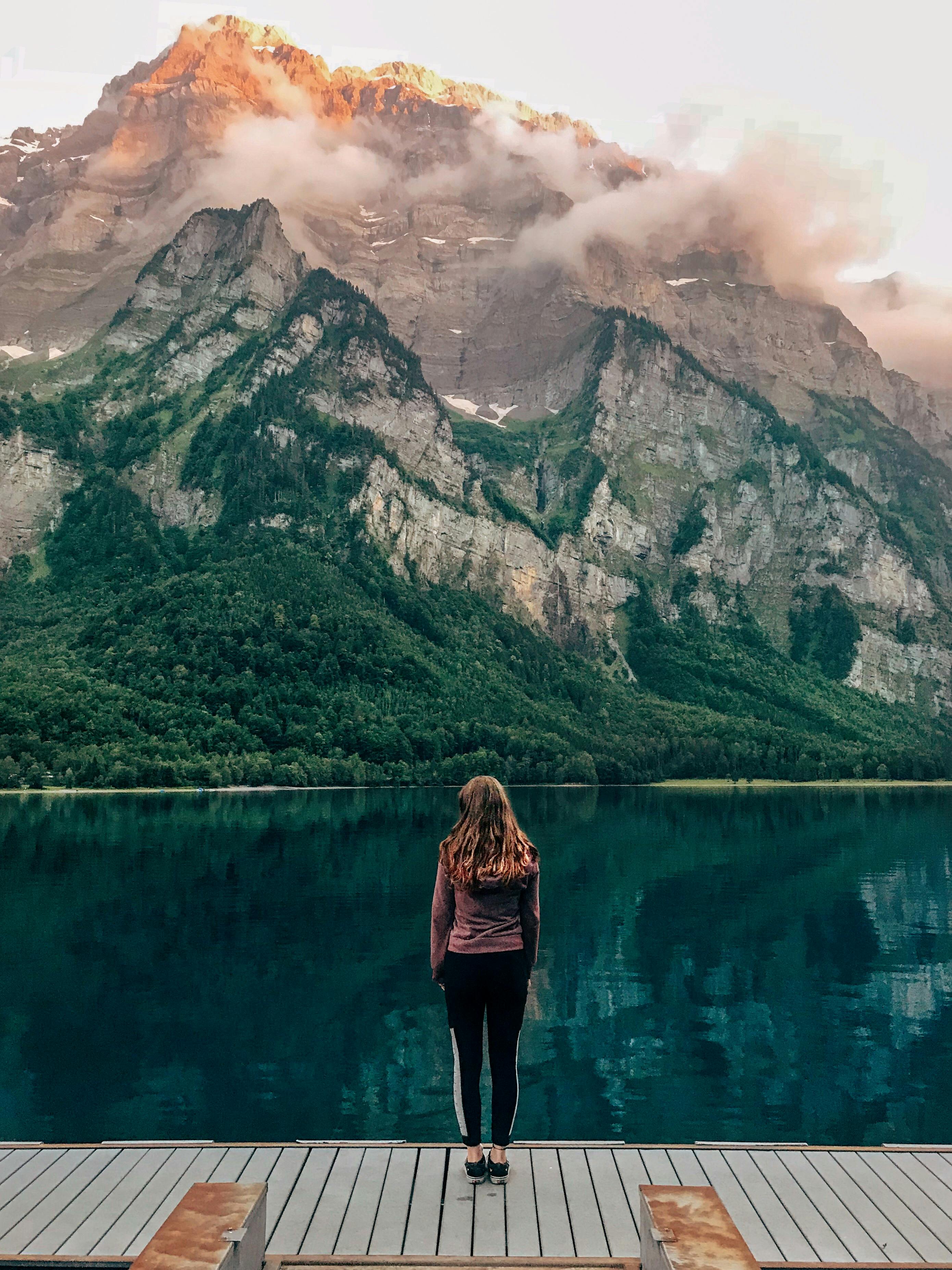 Woman standing at Klöntalersee in Switzerland with scenic mountain background.